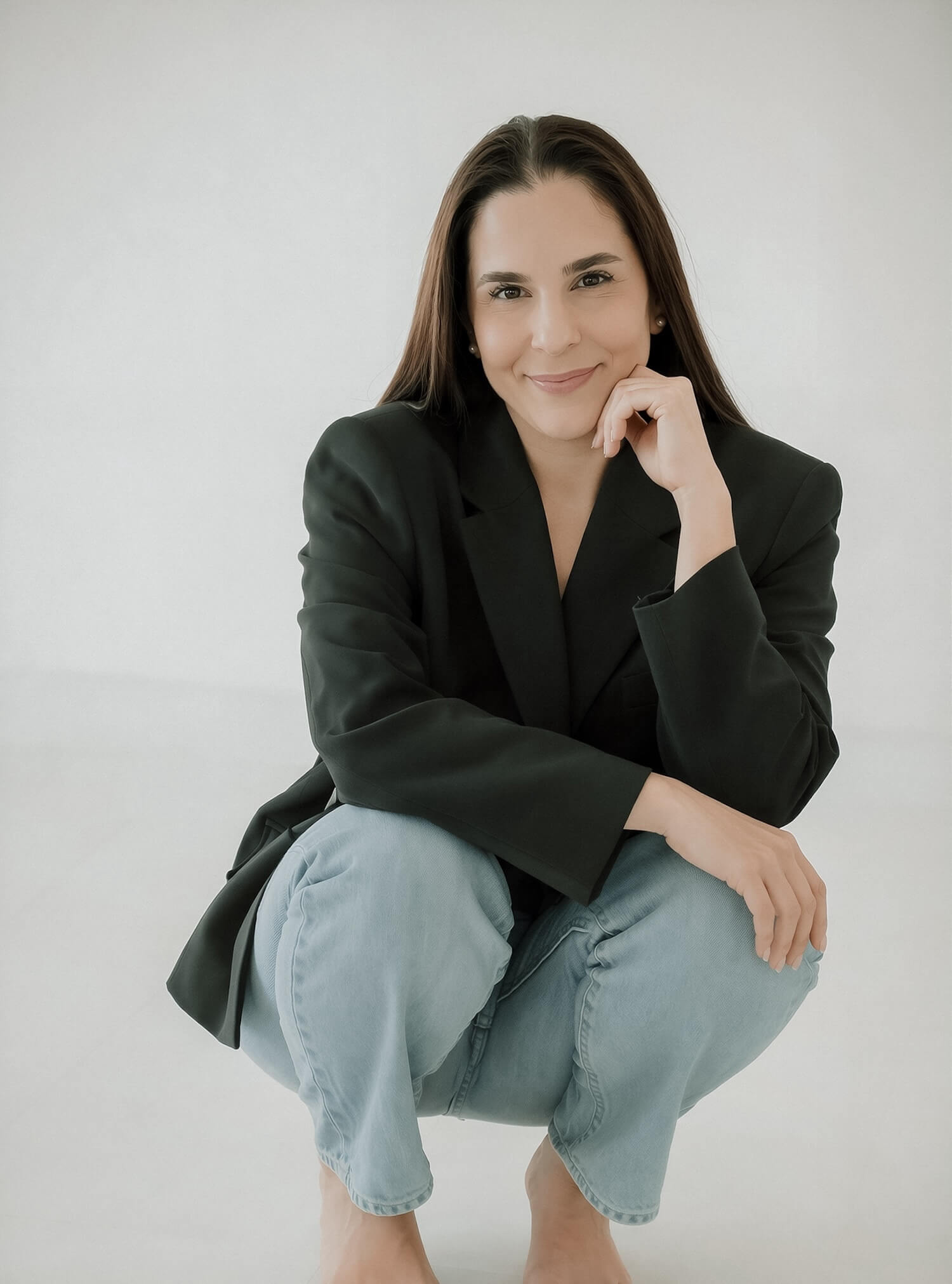 Porträt von mir in dunklem Blazer und Jeans, sitzend vor hellem Hintergrund, mit ruhigem Lächeln und direktem Blick in die Kamera. Das Titelbild des Blogartikels: 37 Fun Facts Über mich.